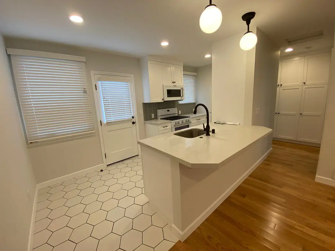 Remodeled Cabrillo Bungalows kitchen with white quartz peninsula, hex tile and oak floors