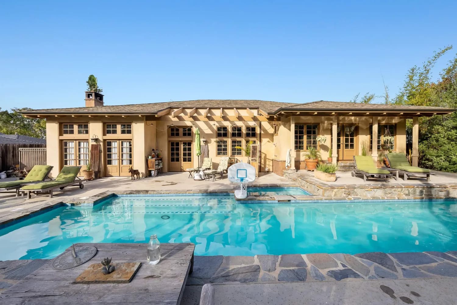Pool and spa framed by the home's stucco rear facade and French-door covered porch