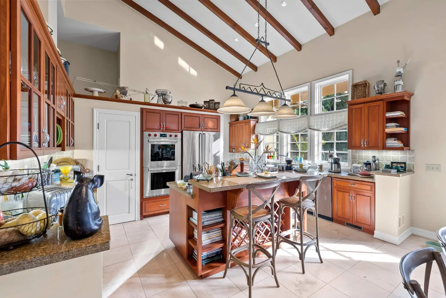 Gourmet kitchen with center island seating, glass-front cabinets, and pot rack lighting
