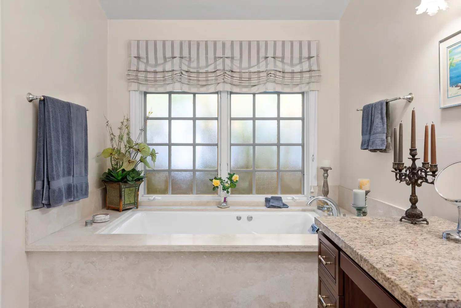Remodeled bathroom with built-in soaking tub, frosted window, and granite vanity