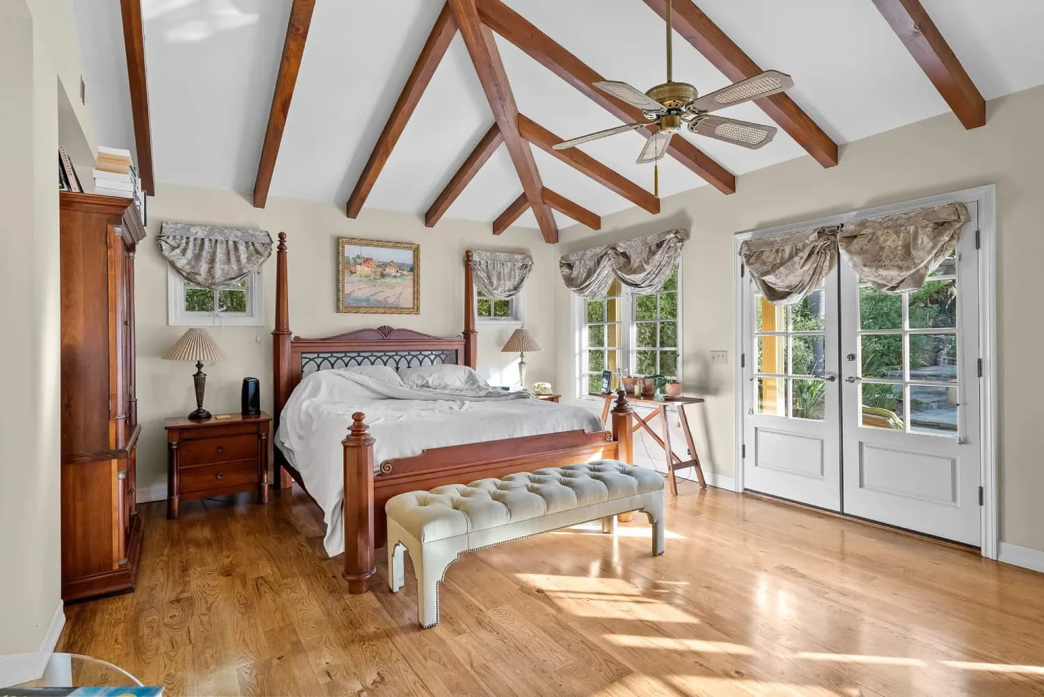 Master bedroom with vaulted exposed-beam ceiling, hardwood floors, and French doors