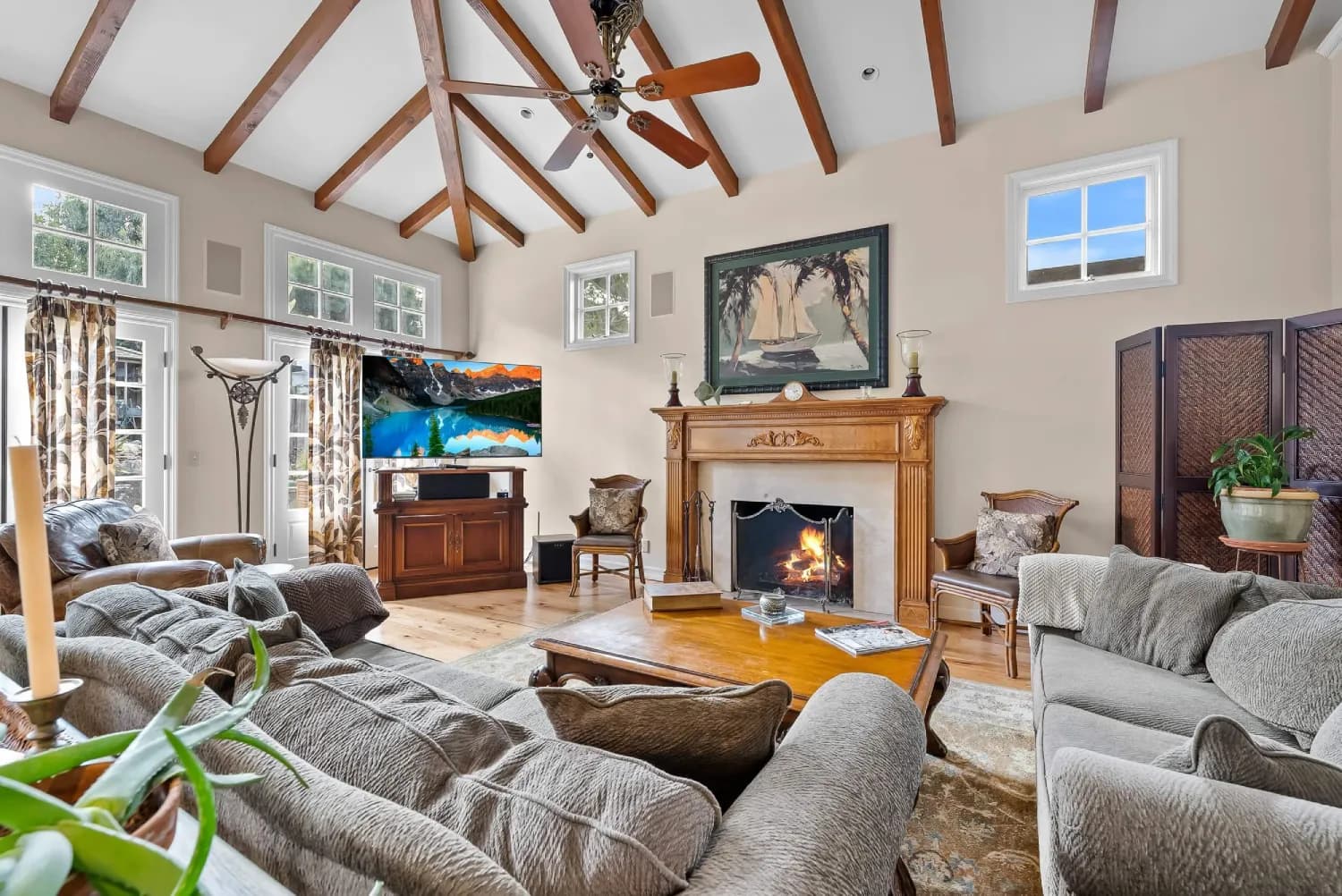 Living room with vaulted beamed ceiling, wood-mantel fireplace, and clerestory windows