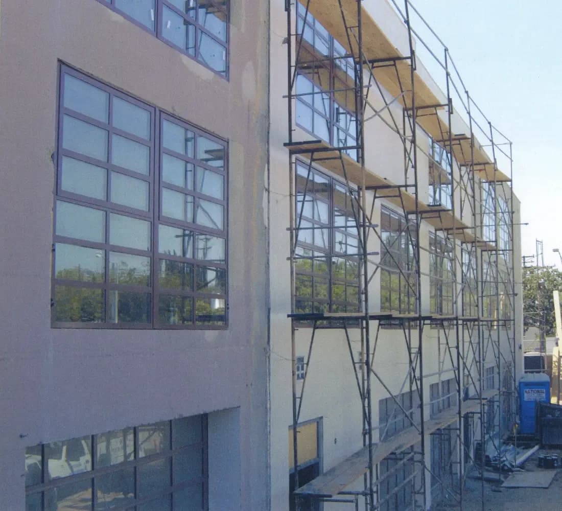 Exterior of the converted concrete loft building with scaffolding and new windows during construction in South Pasadena