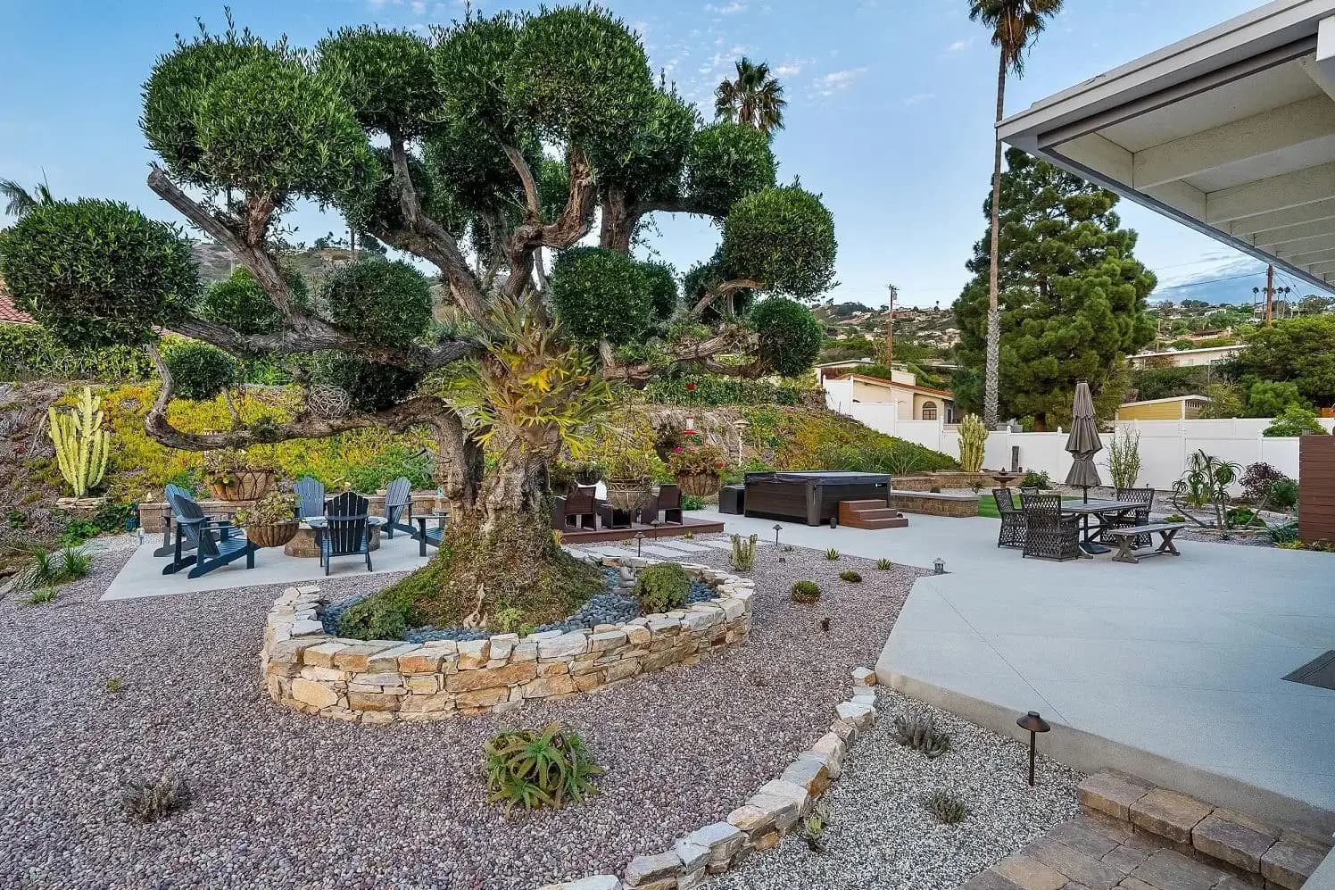 Mature sculpted topiary above a curved stone planter in a rock-and-cactus garden