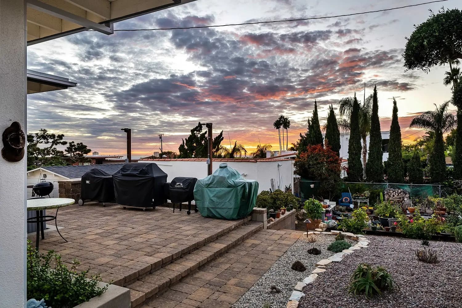 Paver patio with grills and tiered succulent garden beneath a sunset sky