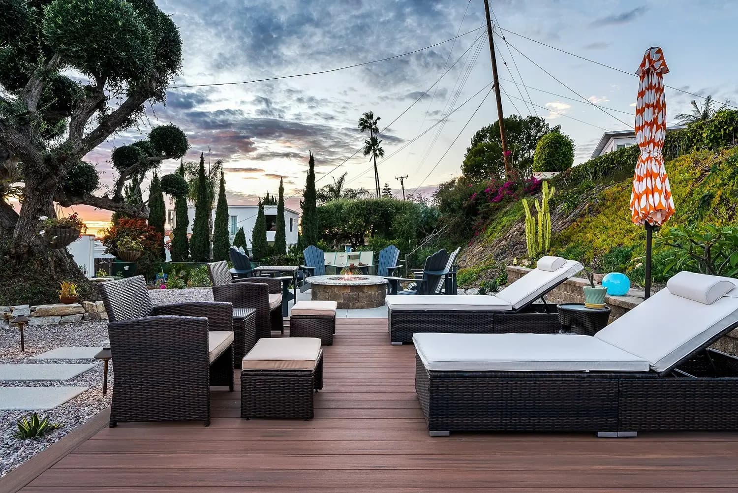 Wood deck with rattan lounge seating and chaise loungers overlooking a planted hillside