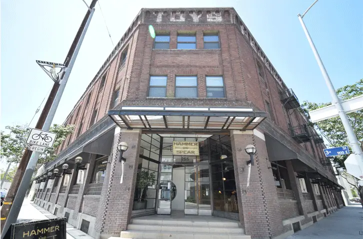 Glass-canopy entrance to the Toy Lofts building with Hammer and Spear ground-floor storefront