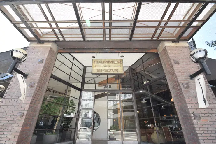 Brick-pillar entry with steel canopy and Hammer and Spear hanging sign at the Toy Lofts