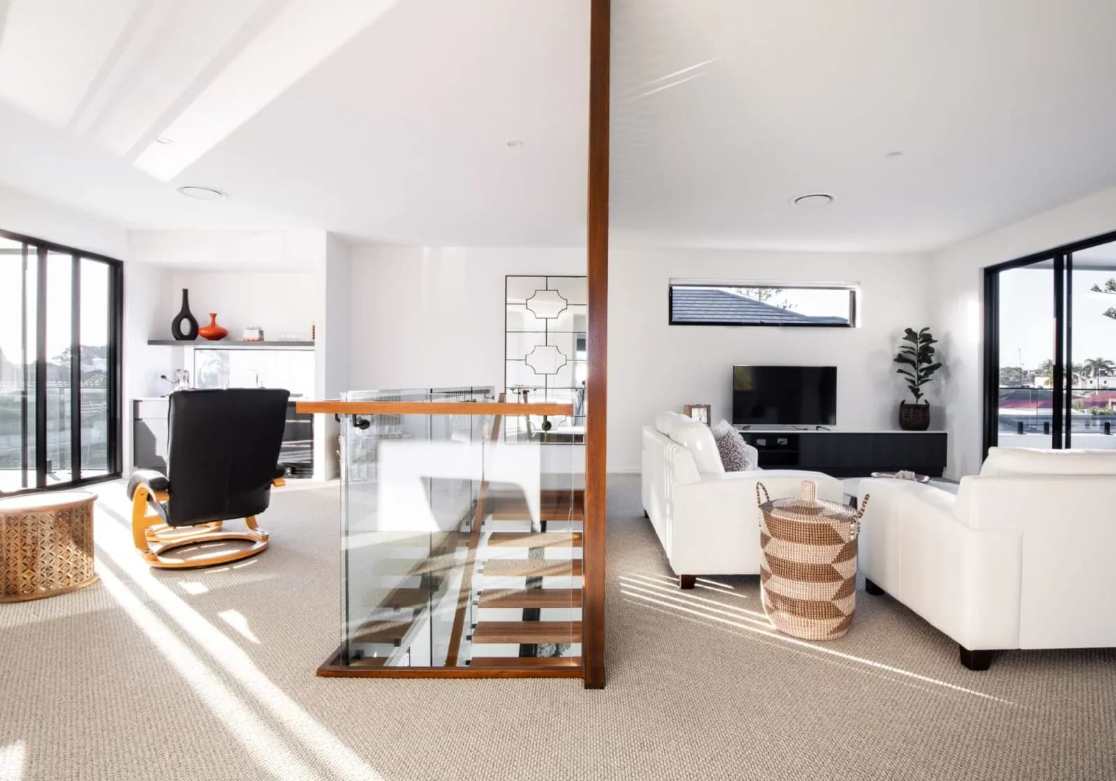 Bright open-plan living and dining room divided by a glass-panel staircase