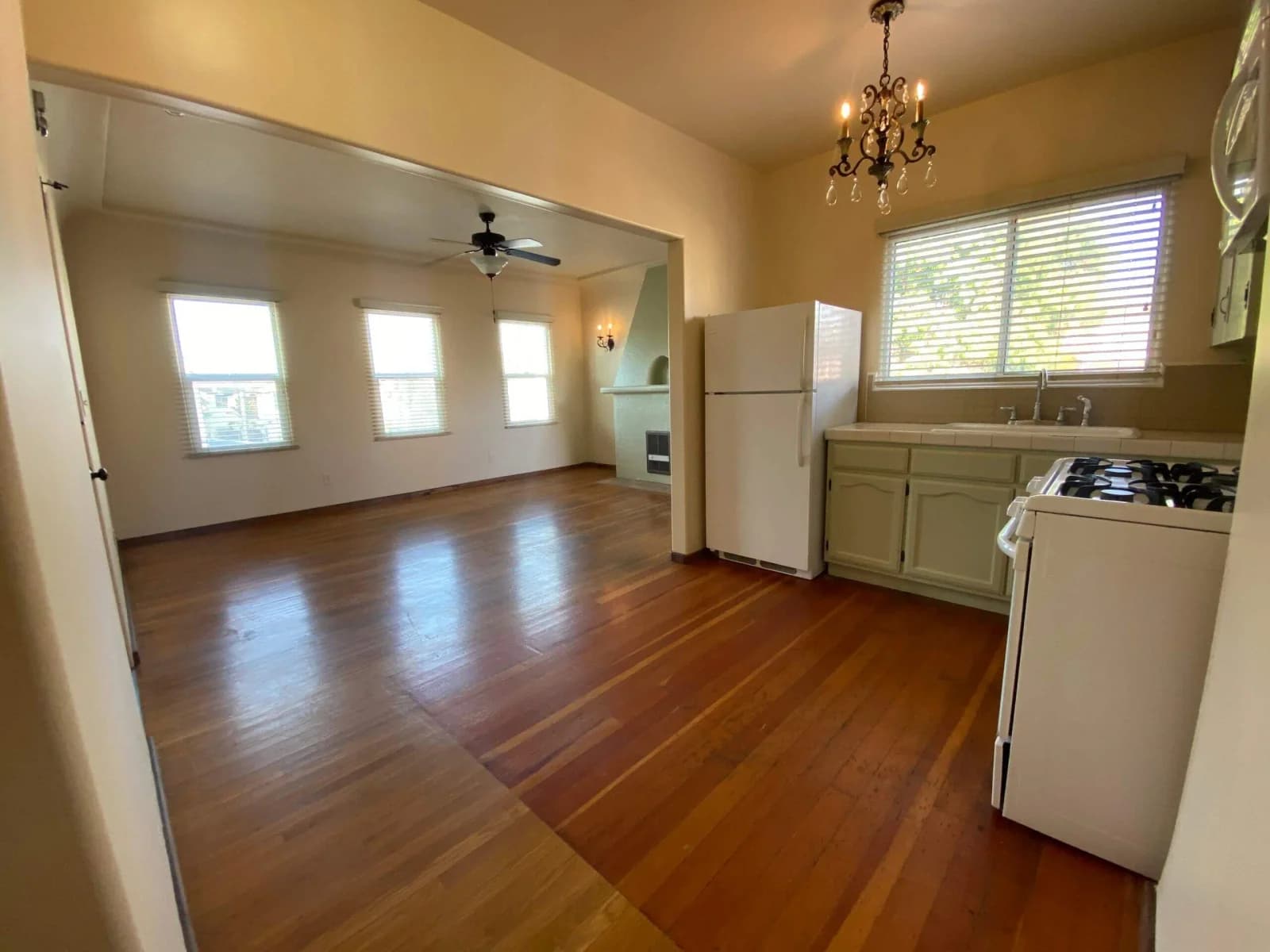 Open living and kitchen area with refinished wood floors and ceiling fan in a Broadway Lofts apartment