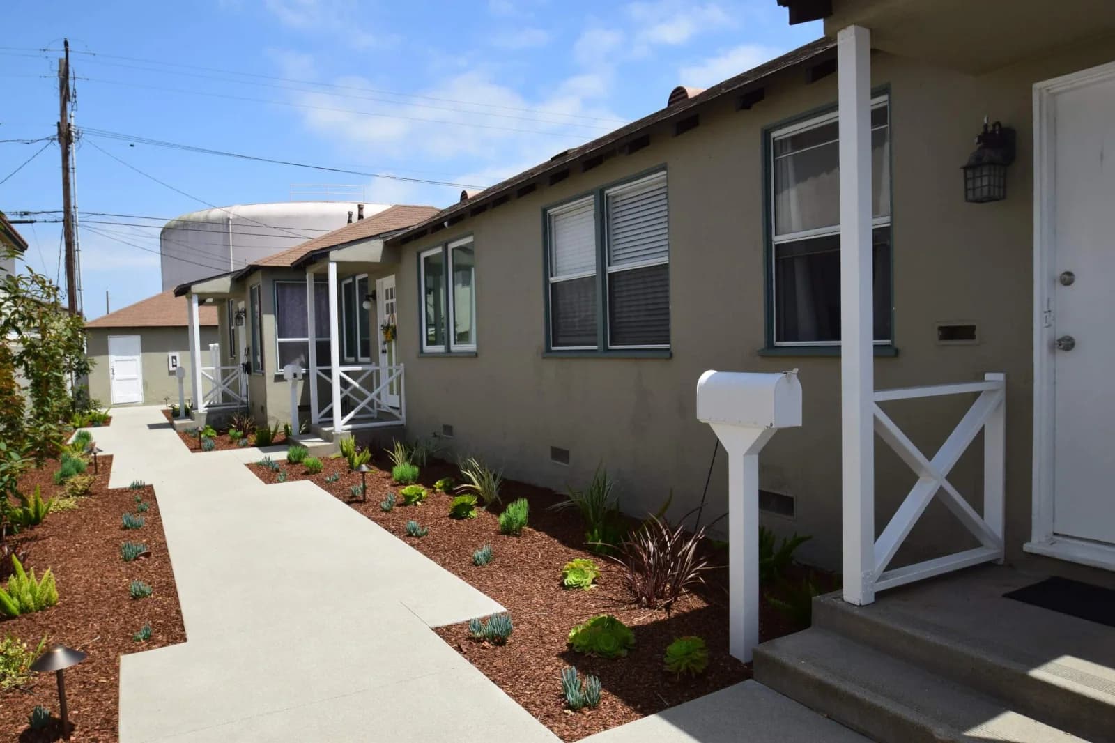 Row of restored Cabrillo Bungalows cottages along a landscaped walkway under blue sky
