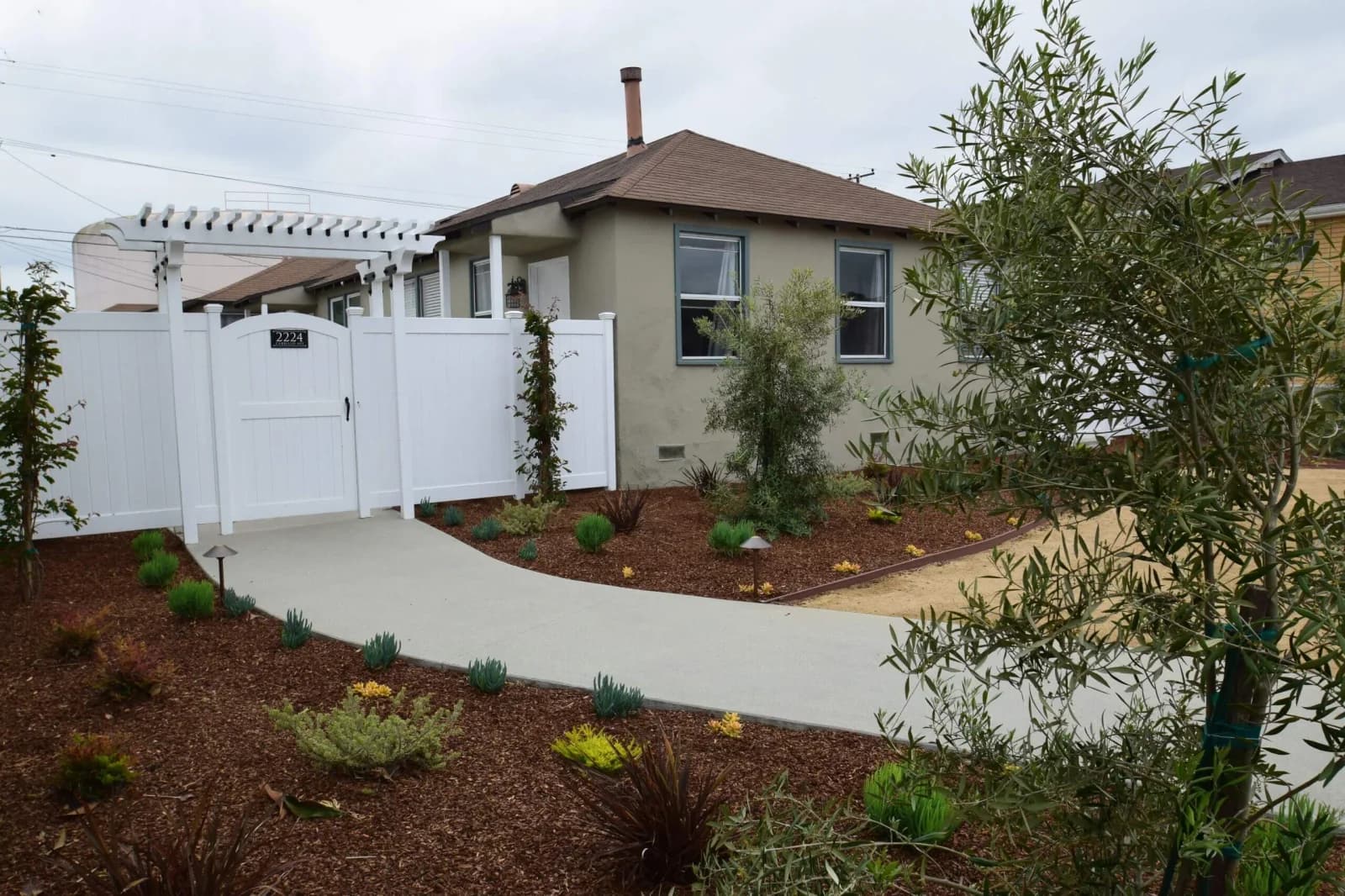 Renovated Cabrillo Bungalows cottage in San Pedro with white pergola gate and drought-tolerant front yard