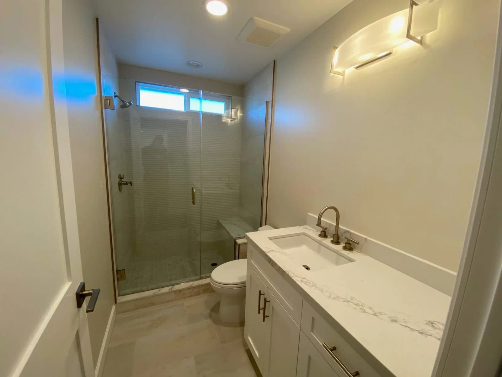 Modern Penmar Lofts bathroom with glass shower, marble-look vanity, and brushed-nickel fixtures