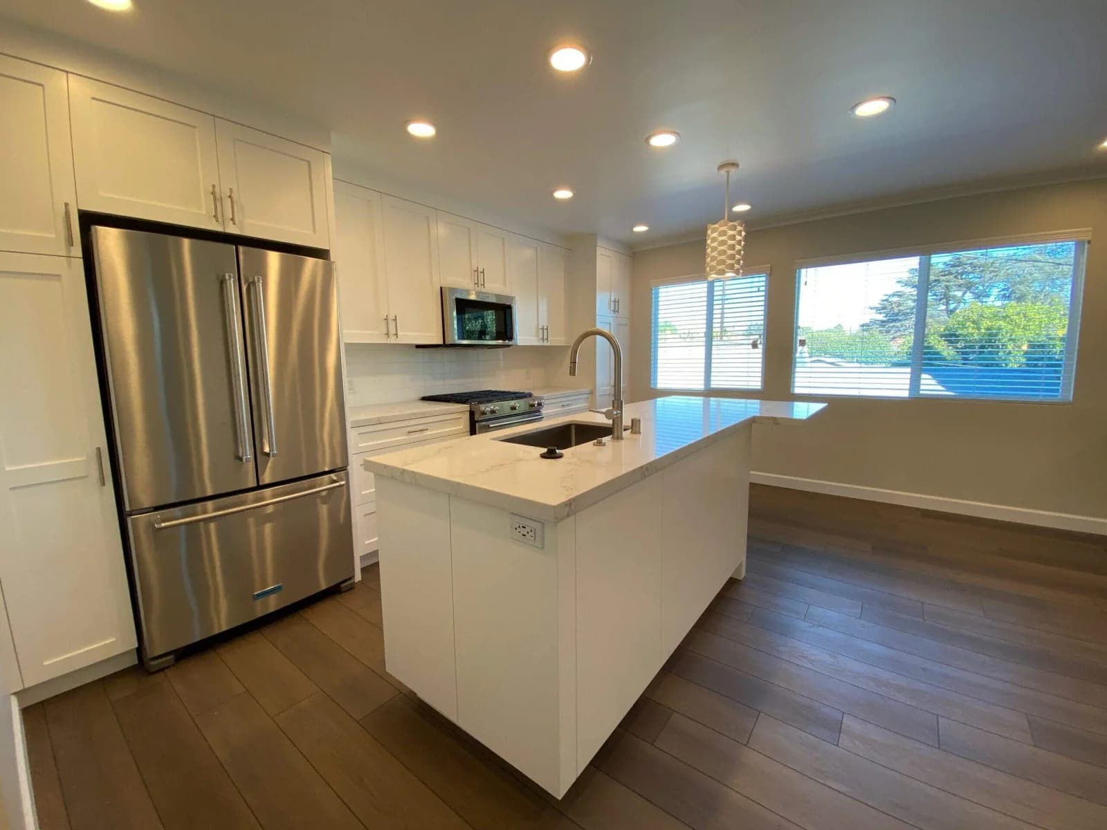 Penmar Lofts kitchen with white quartz island, stainless French-door refrigerator, and bright windows