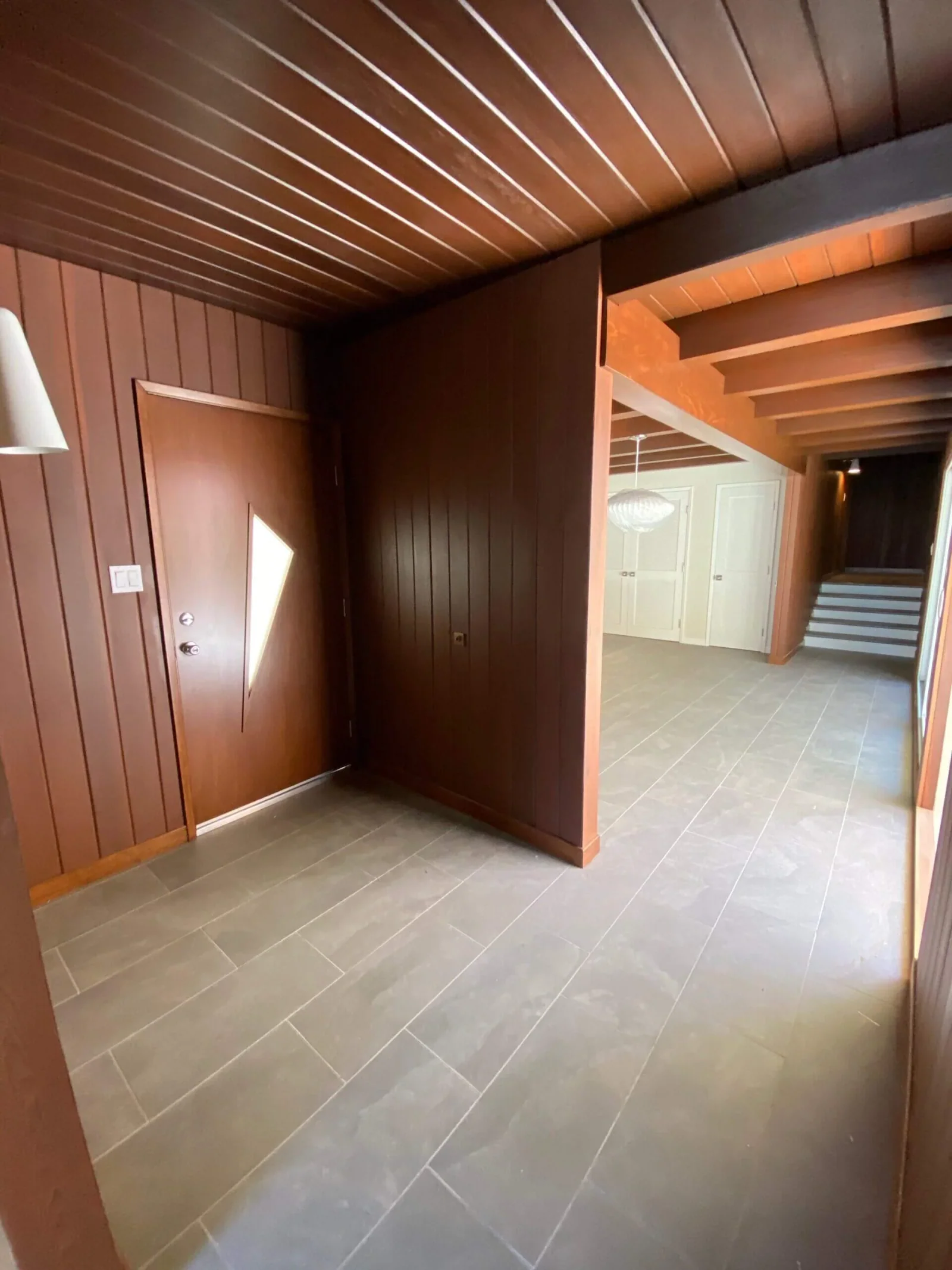 Wood-paneled entry hall with tile floor opening to a living area and staircase at South Redondo Triplex