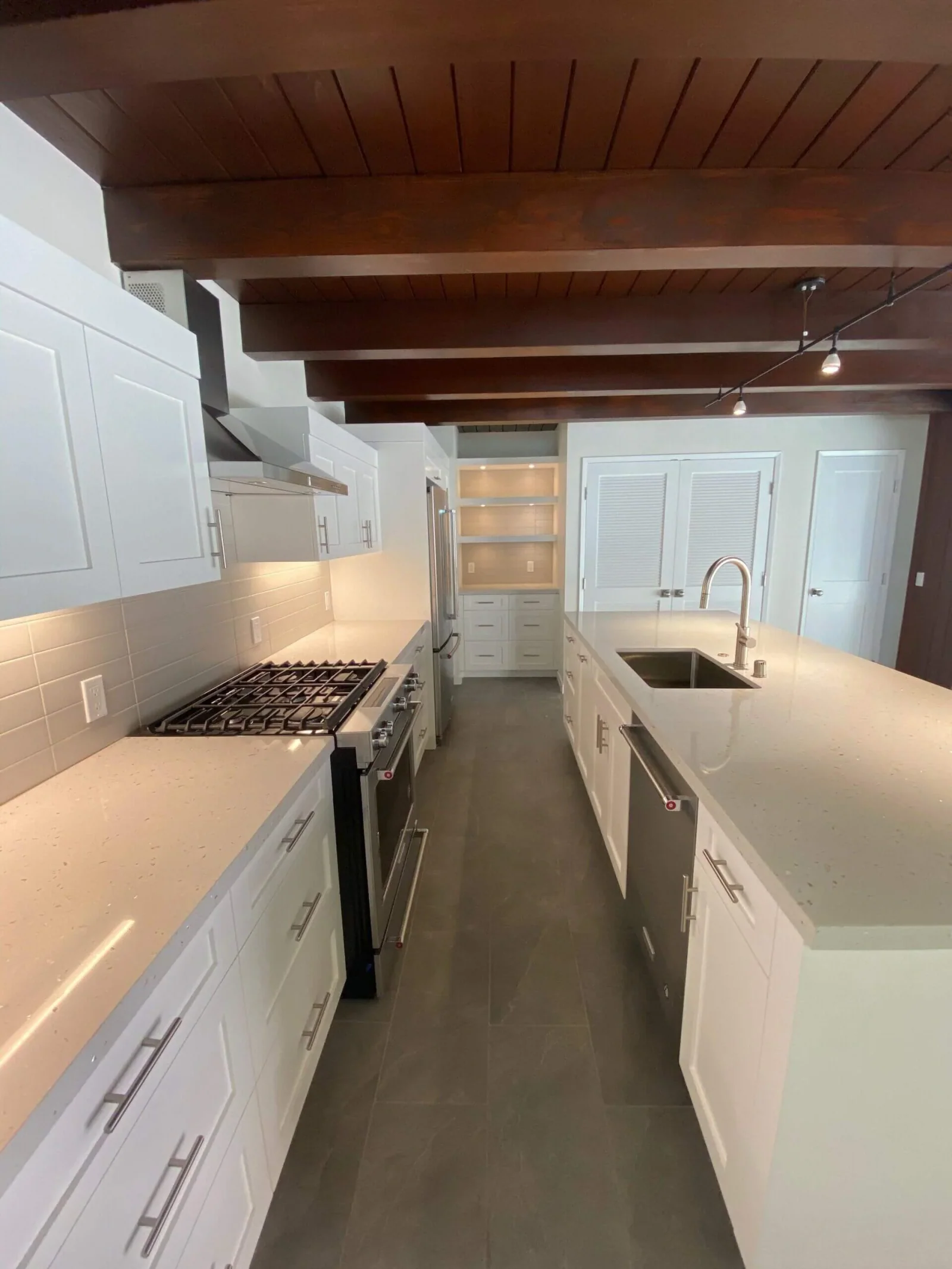 Galley kitchen with quartz island, gas range, and stainless hood under a wood-beam ceiling at South Redondo Triplex