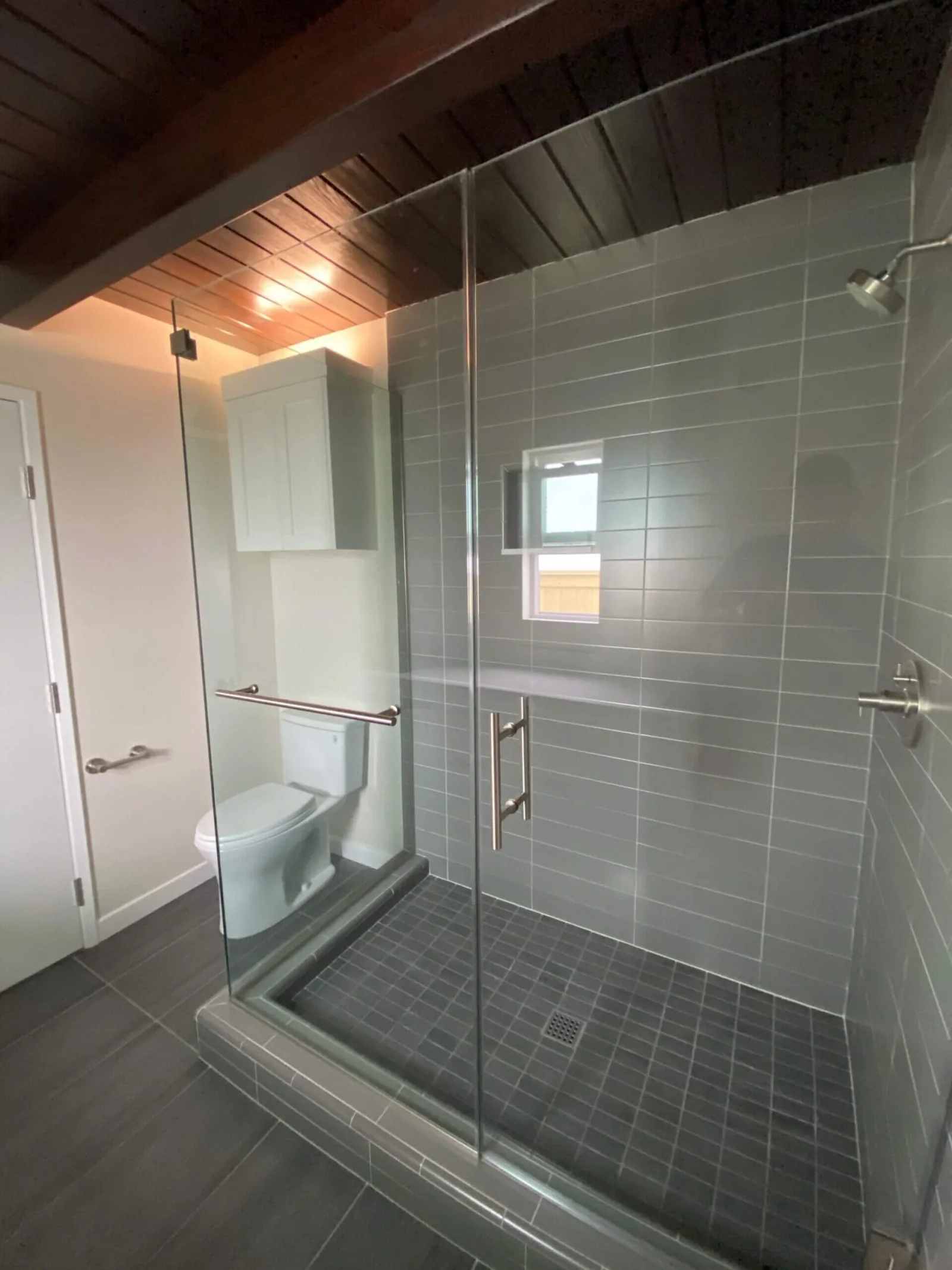 Renovated bathroom with glass walk-in shower, gray tile, and wood plank ceiling at South Redondo Triplex