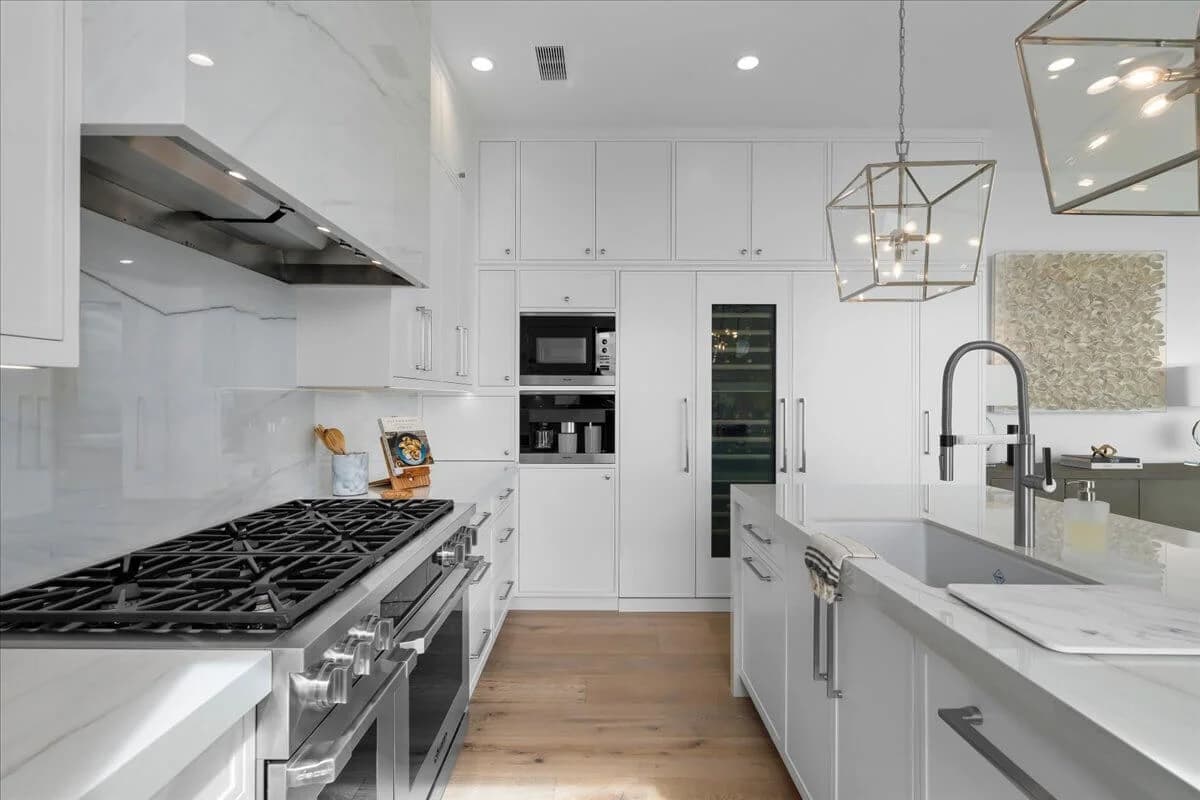 Kitchen with pro gas range, stainless hood, built-in wine fridge, and marble backsplash