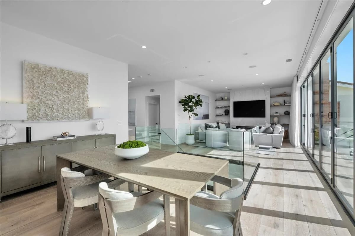 Dining area overlooking a glass-railed stairwell and living room with sliding glass wall