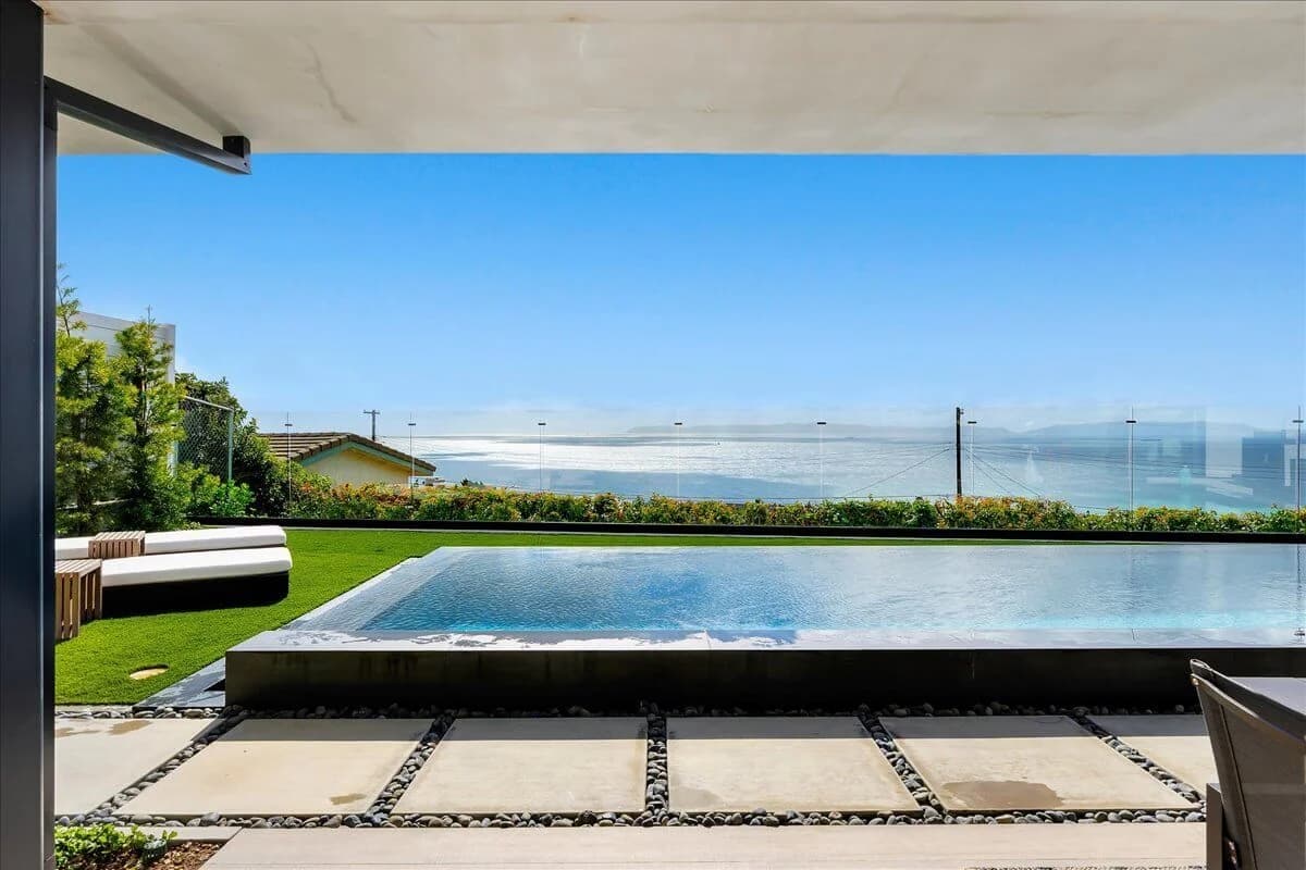 Covered patio framing the infinity pool, lawn, and ocean horizon beyond