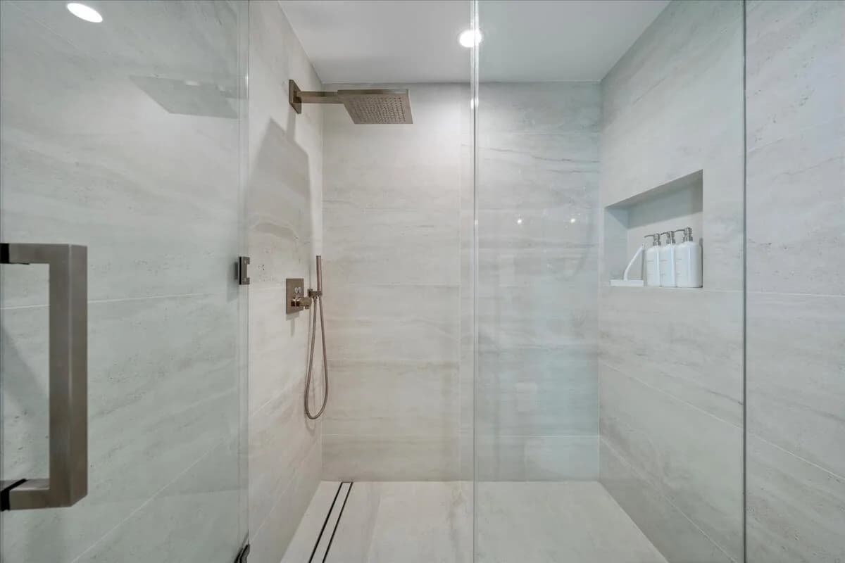 Walk-in shower with floor-to-ceiling stone-look porcelain tile and frameless glass enclosure