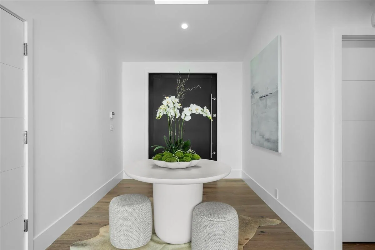 Entry foyer with skylight, round pedestal table, and black front door beyond