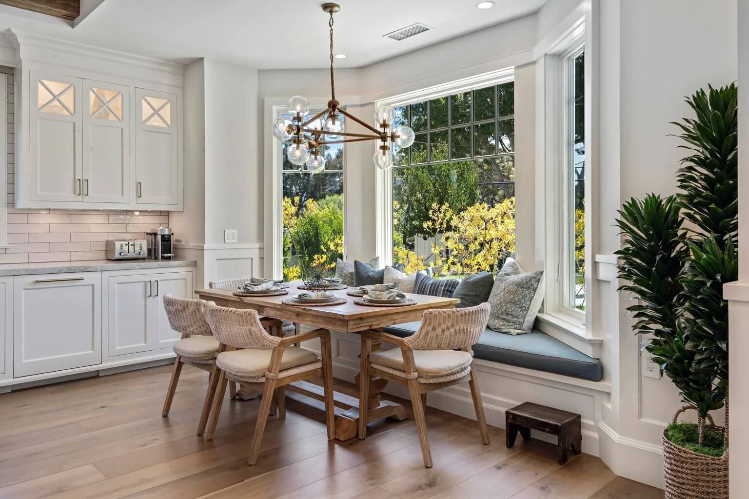Sunny breakfast nook with round table and bay-window bench seating beside the kitchen