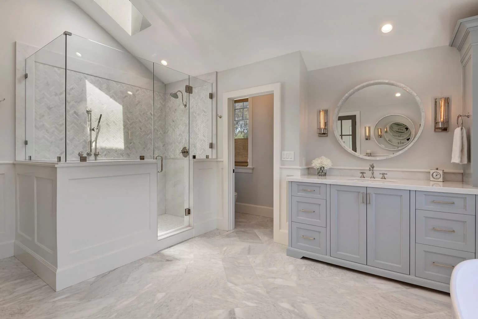 Master bathroom with glass walk-in shower, gray vanity, and marble tile floor