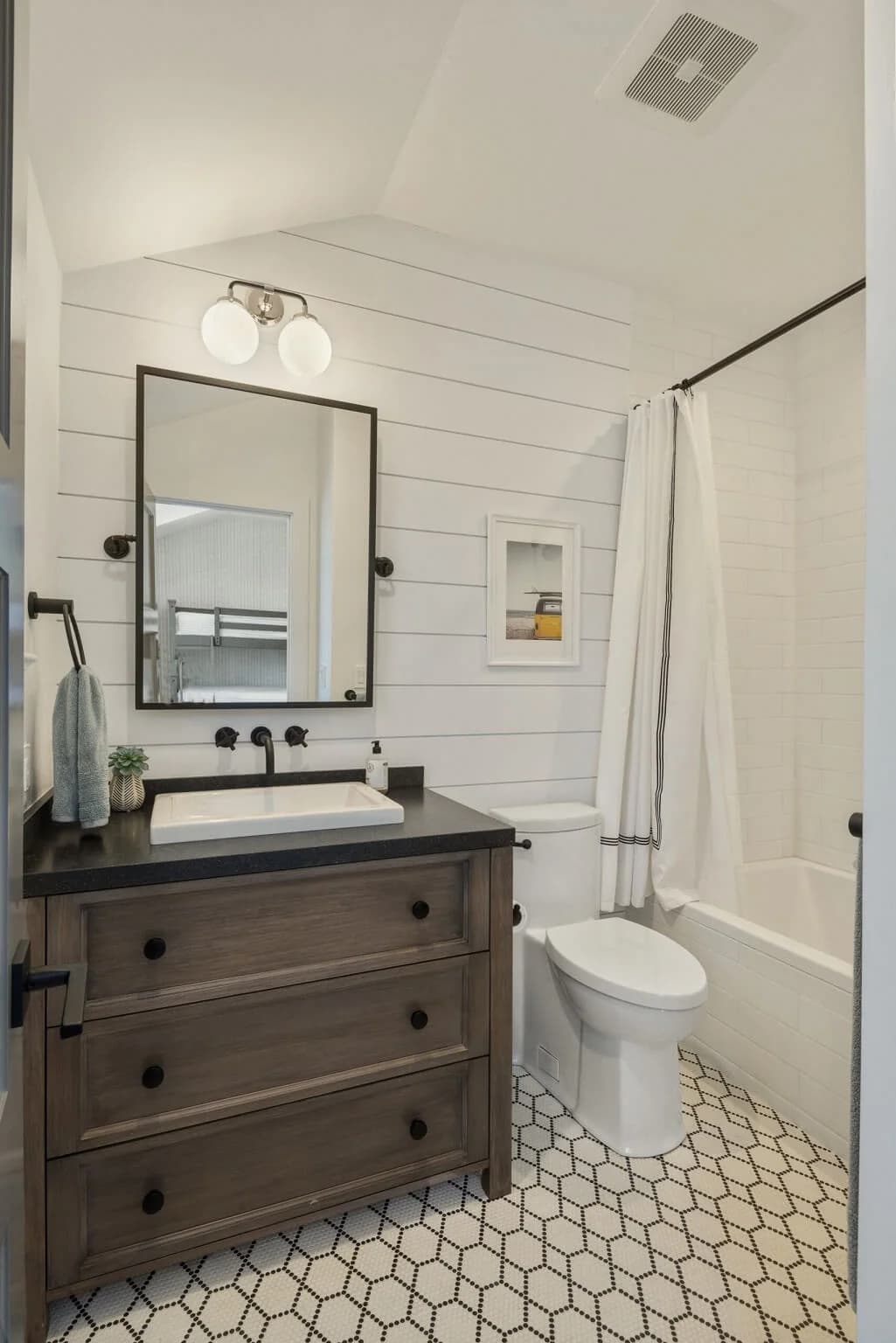 Bathroom with white shiplap walls, dark wood vanity, and a subway-tiled shower tub combo