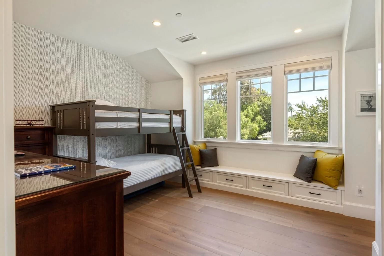 Kids' bedroom with wood bunk beds and built-in window-seat storage bench
