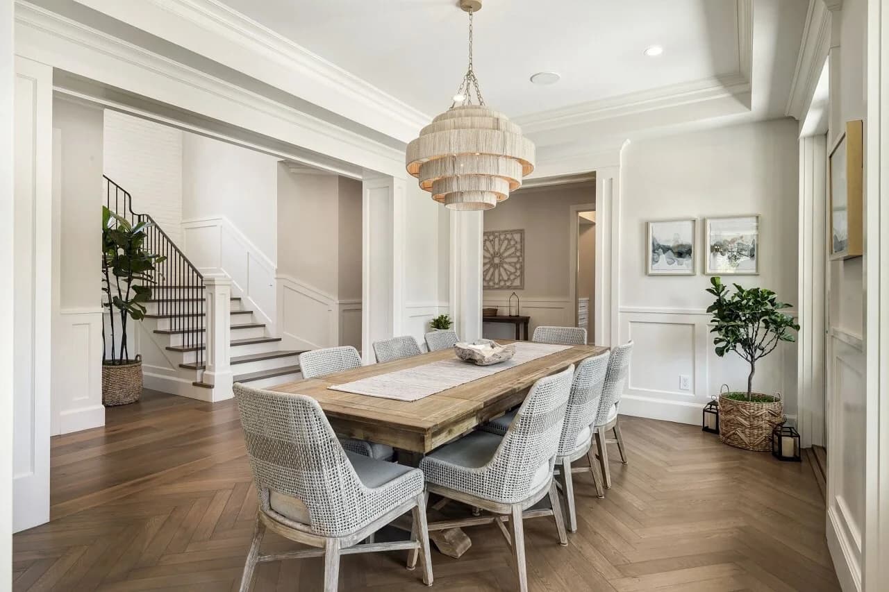 Formal dining room with woven beaded chandelier, long wood table, and herringbone floors
