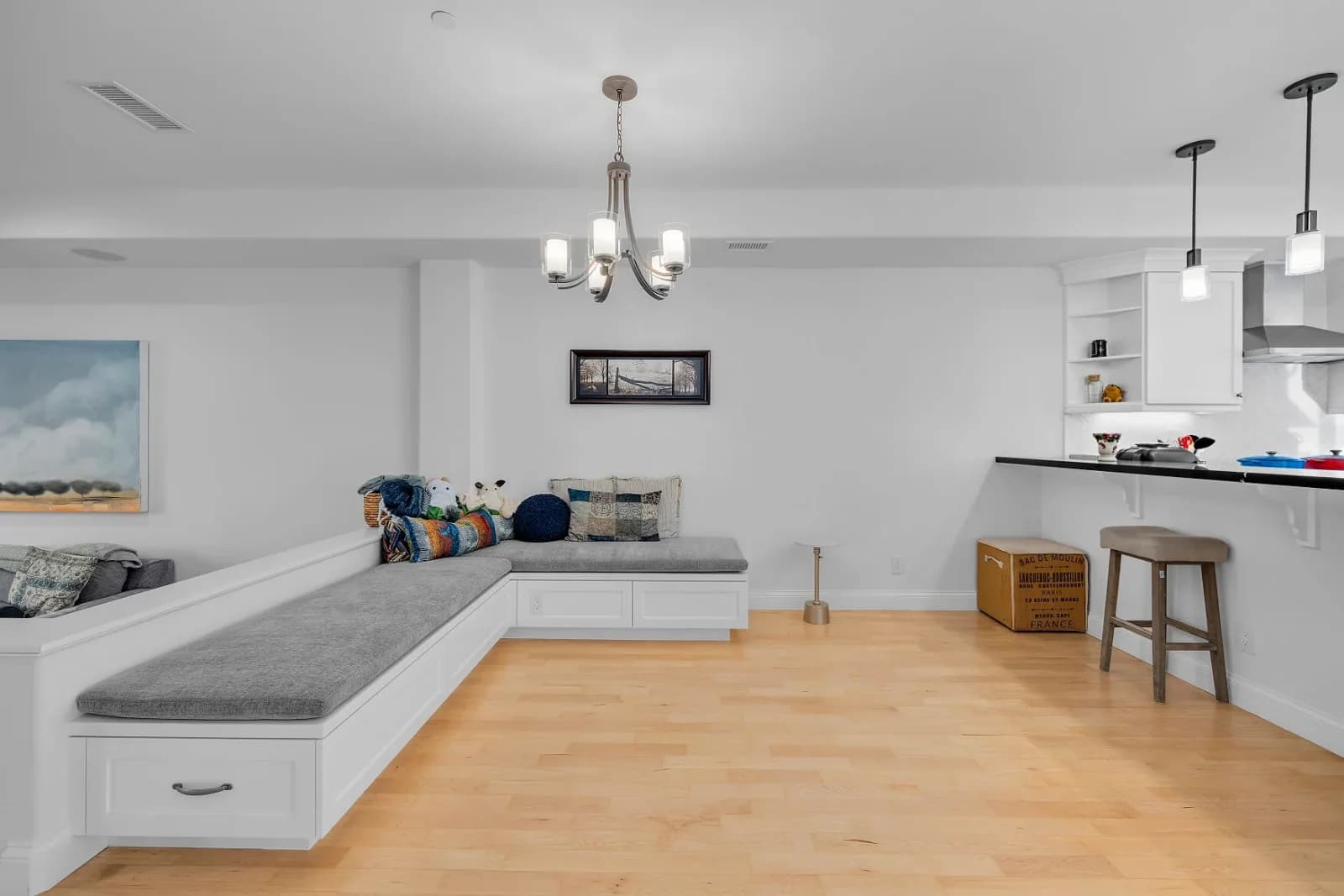 Open living room with custom white built-in bench seating and maple floors