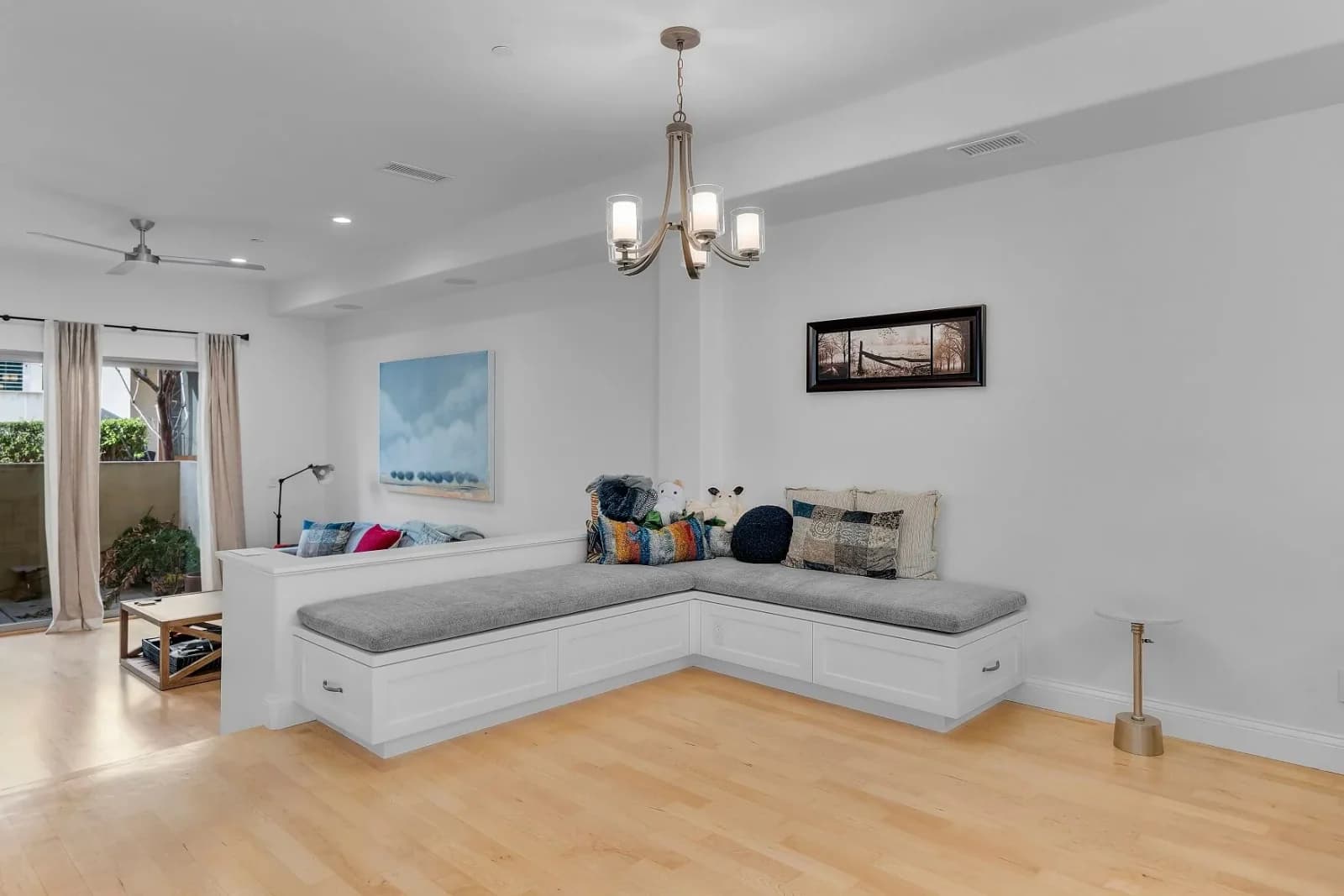 Living room with L-shaped built-in bench, chandelier and maple flooring
