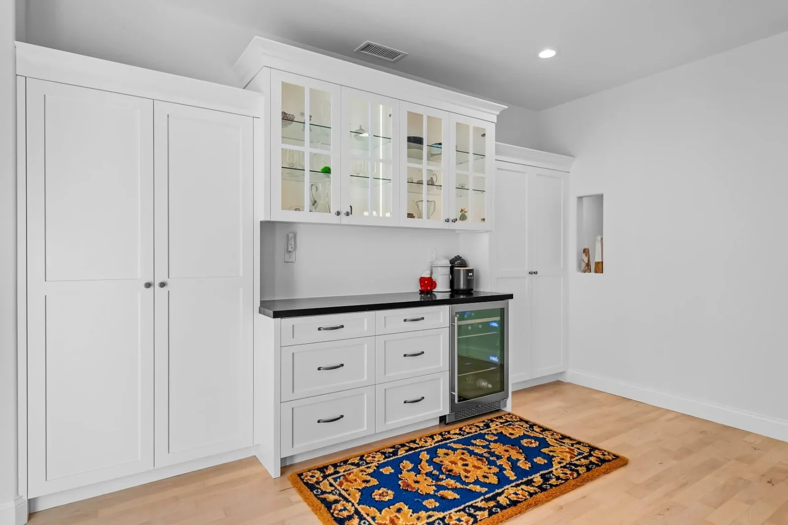 Custom white cabinetry with glass display uppers, beverage cooler and pantry doors