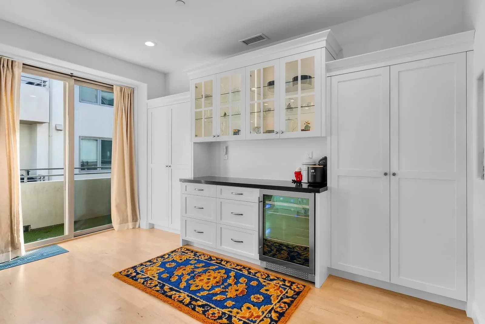 Built-in dining hutch with glass-front cabinets, wine fridge and patio access