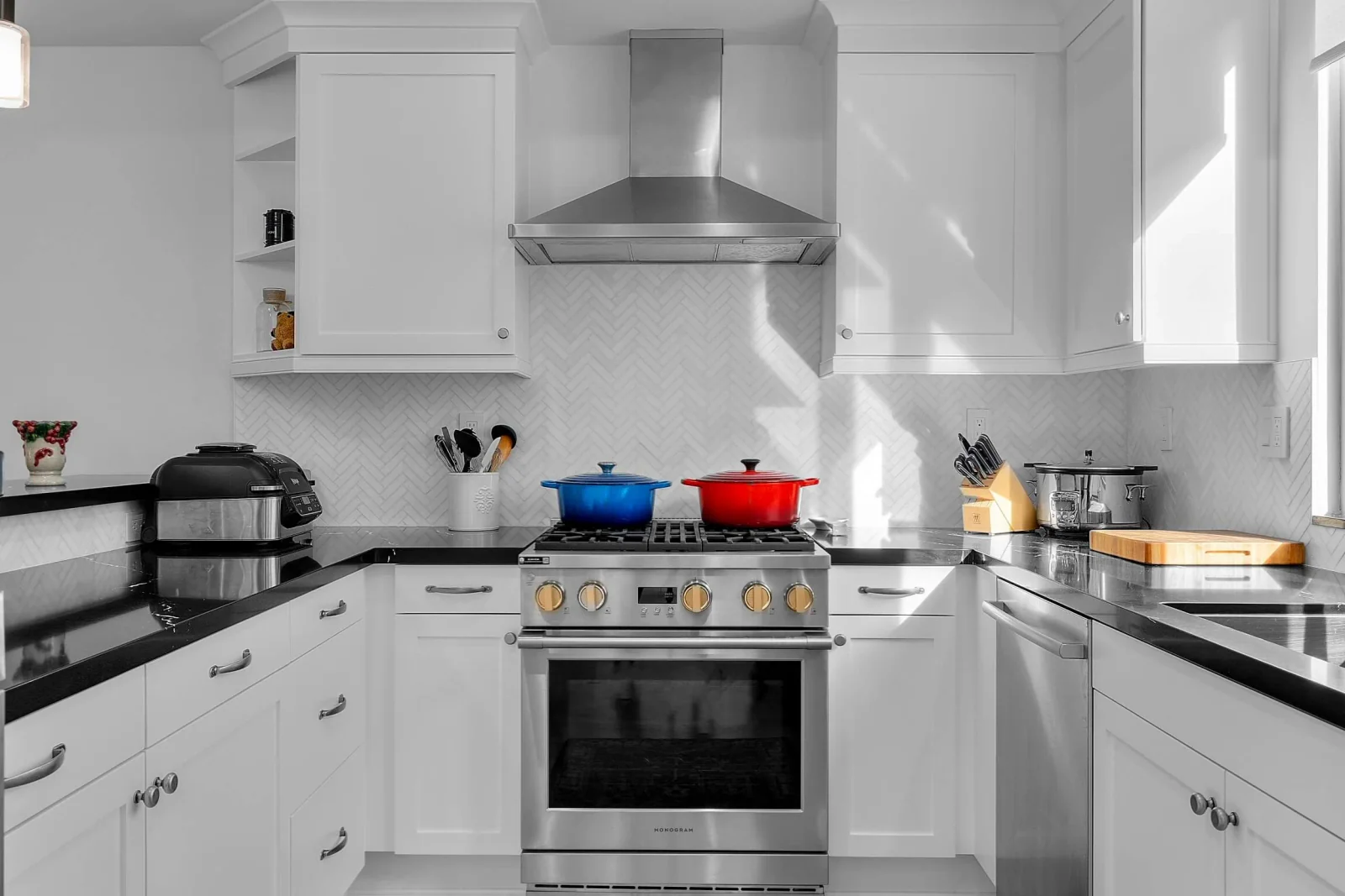 White kitchen with stainless range, vent hood and herringbone tile backsplash