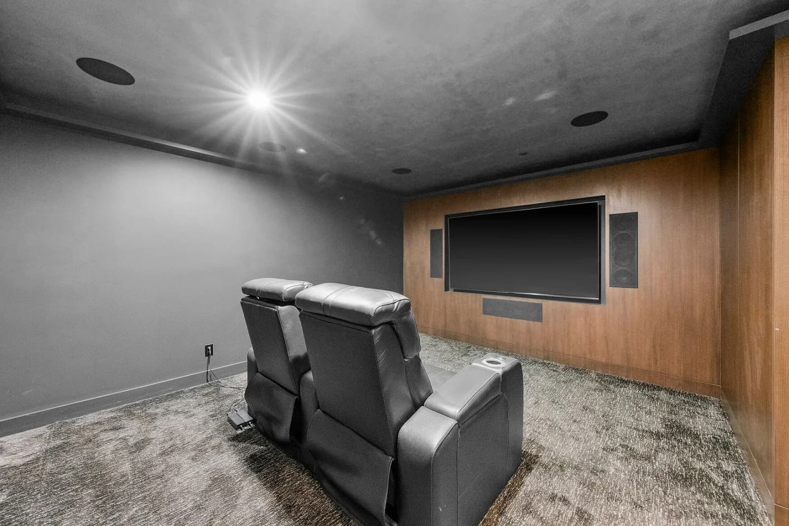 Home theater with reclining leather seats facing a wood-paneled media wall