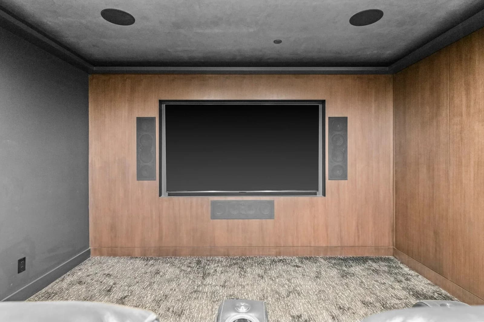 Custom home theater with wood-paneled feature wall and mounted display