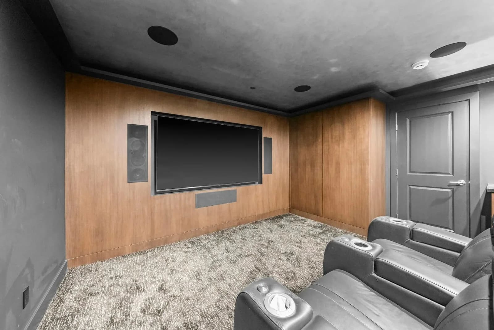 Media room with wood-paneled wall, large flat-screen and plush carpet seating
