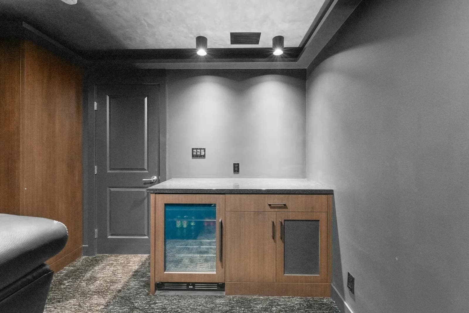 Home theater wet bar with wood-front cabinetry and built-in beverage fridge