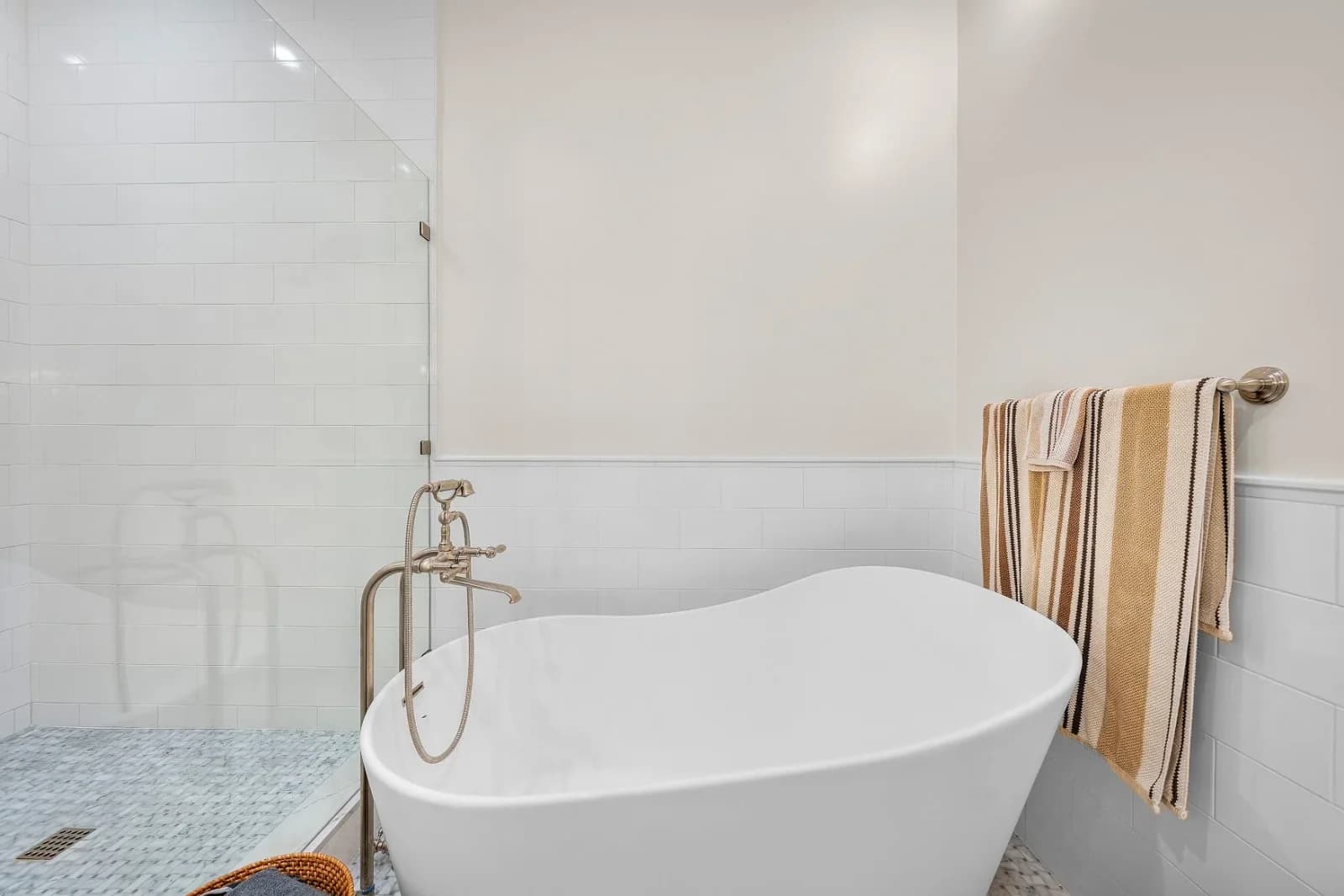 Freestanding slipper soaking tub beside a glass walk-in shower with marble floor