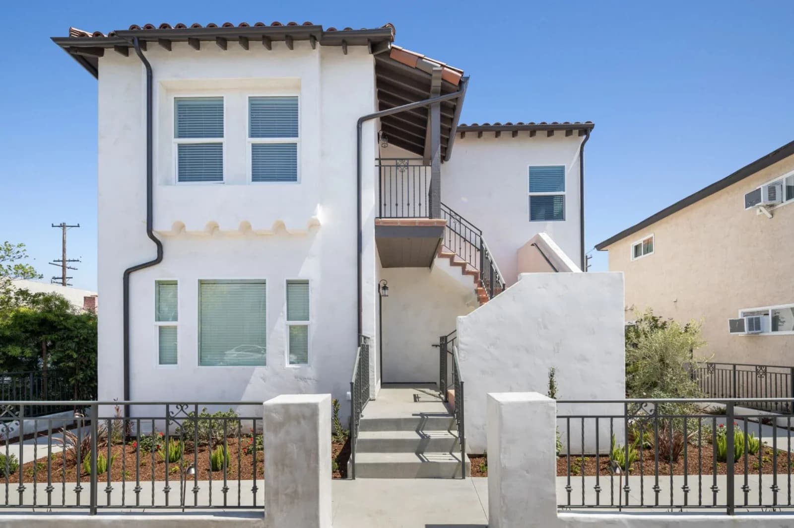 Renovated four-unit Spanish-style exterior with fresh stucco and new wrought-iron railings