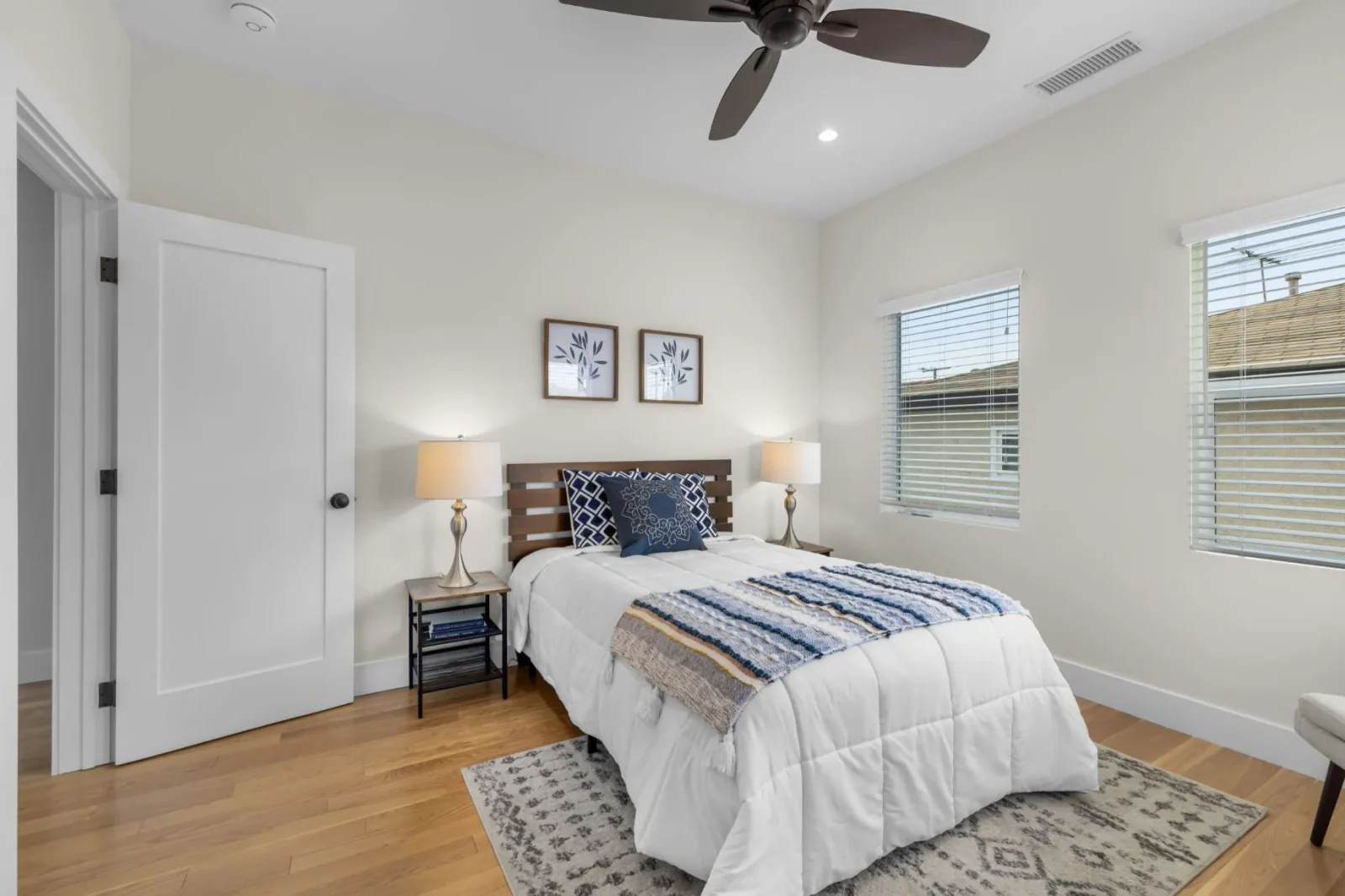 Second staged bedroom with hardwood flooring, twin nightstands, and dual-pane windows