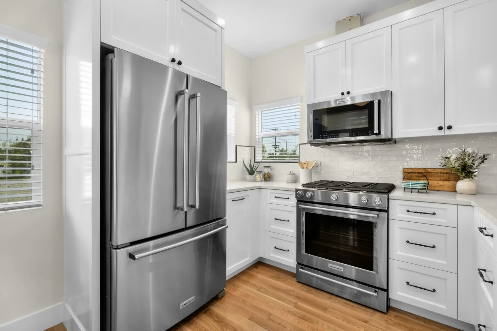 Kitchen with stainless steel refrigerator, gas range, and microwave amid white cabinetry
