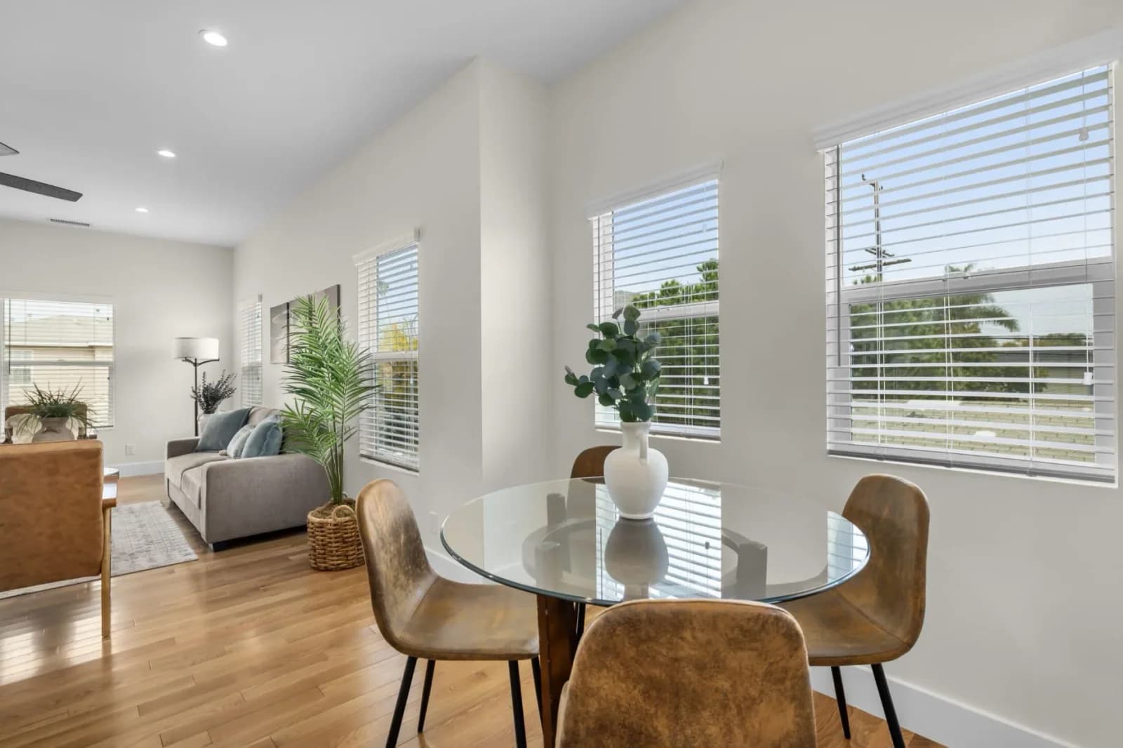 Open dining nook with glass table flowing into a staged living room with large windows