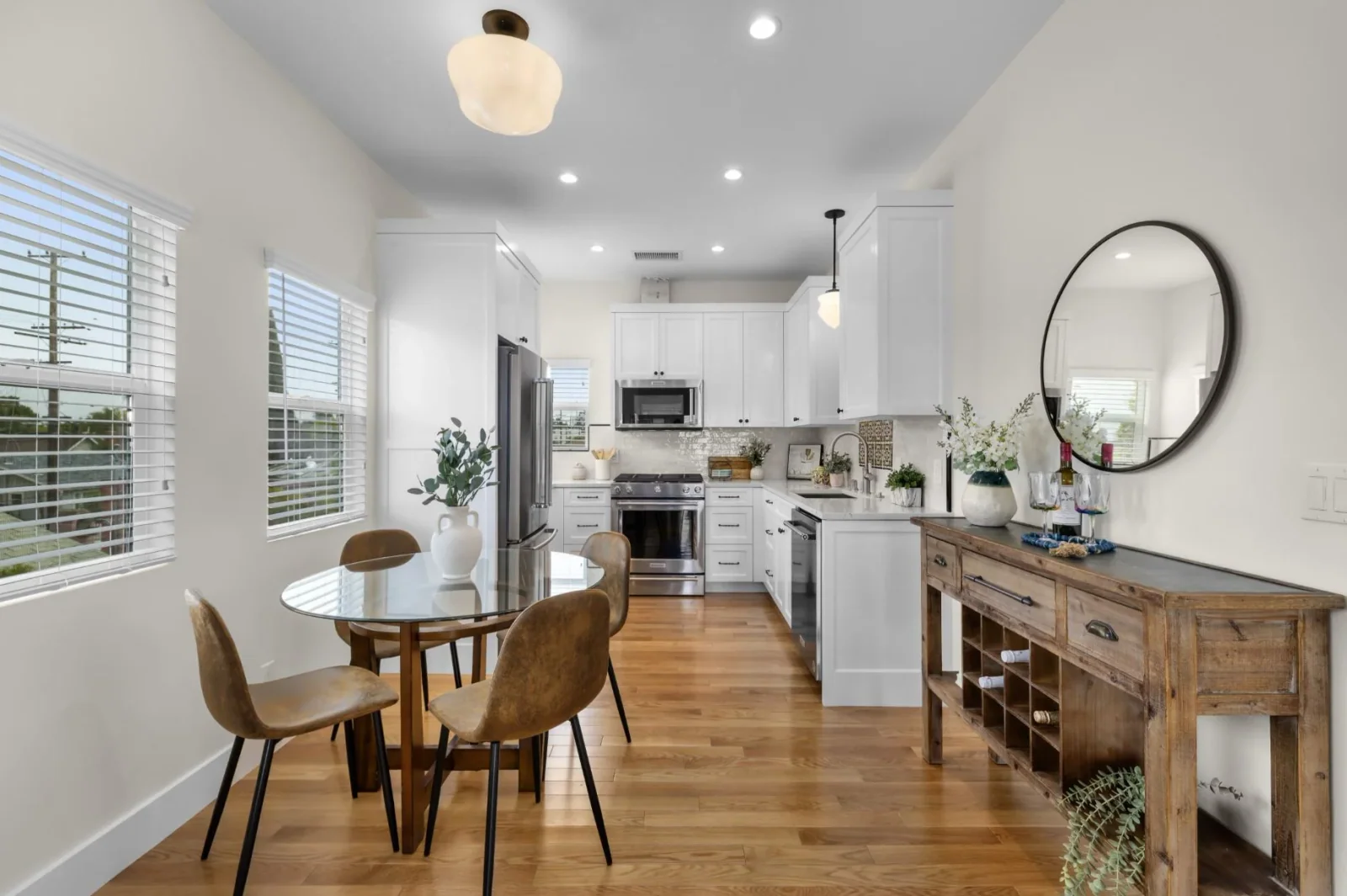 Open-concept kitchen and dining area with hardwood floors and round pendant lighting
