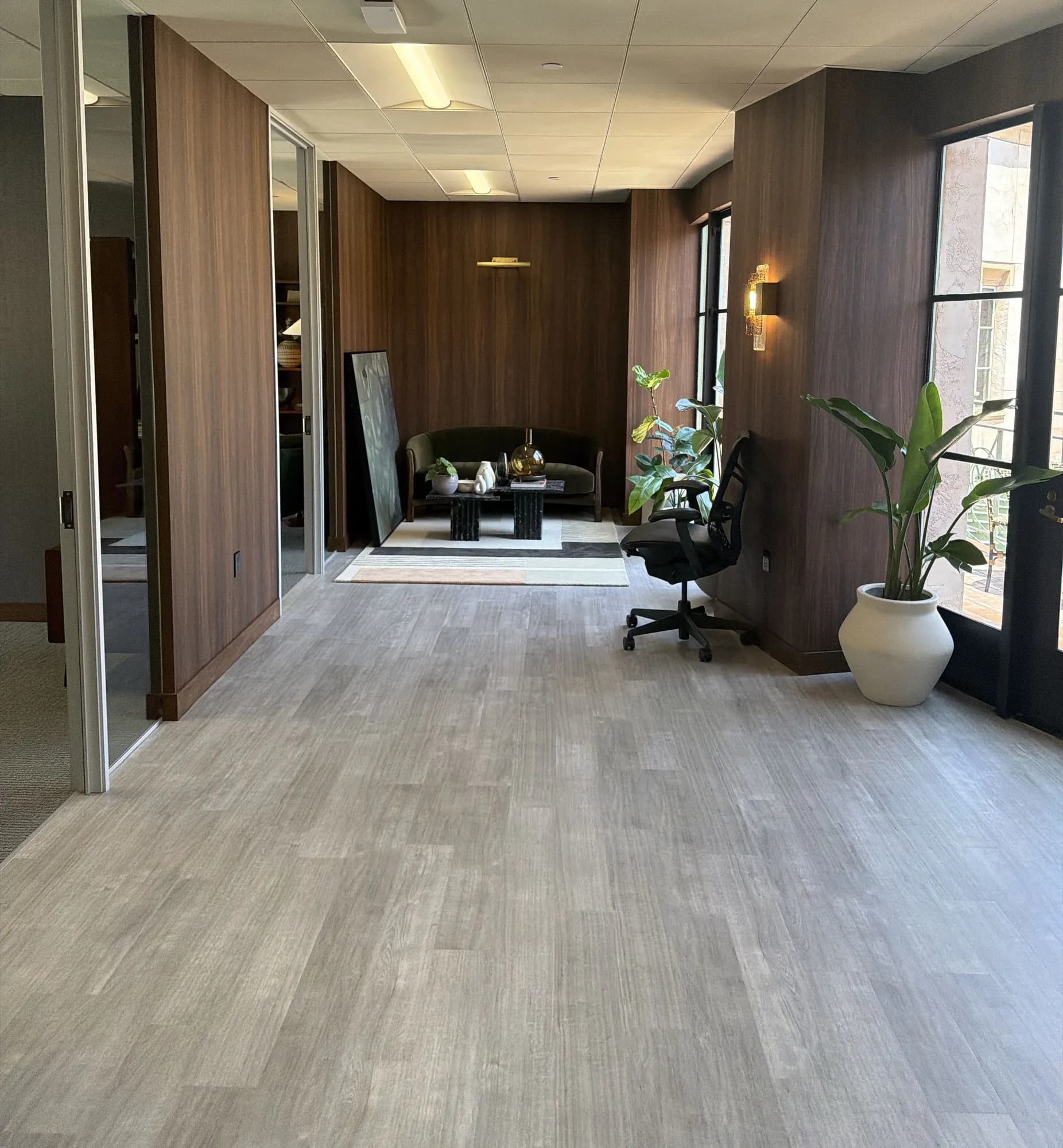 Corridor with walnut wall panels and wood-look flooring leading to a lounge