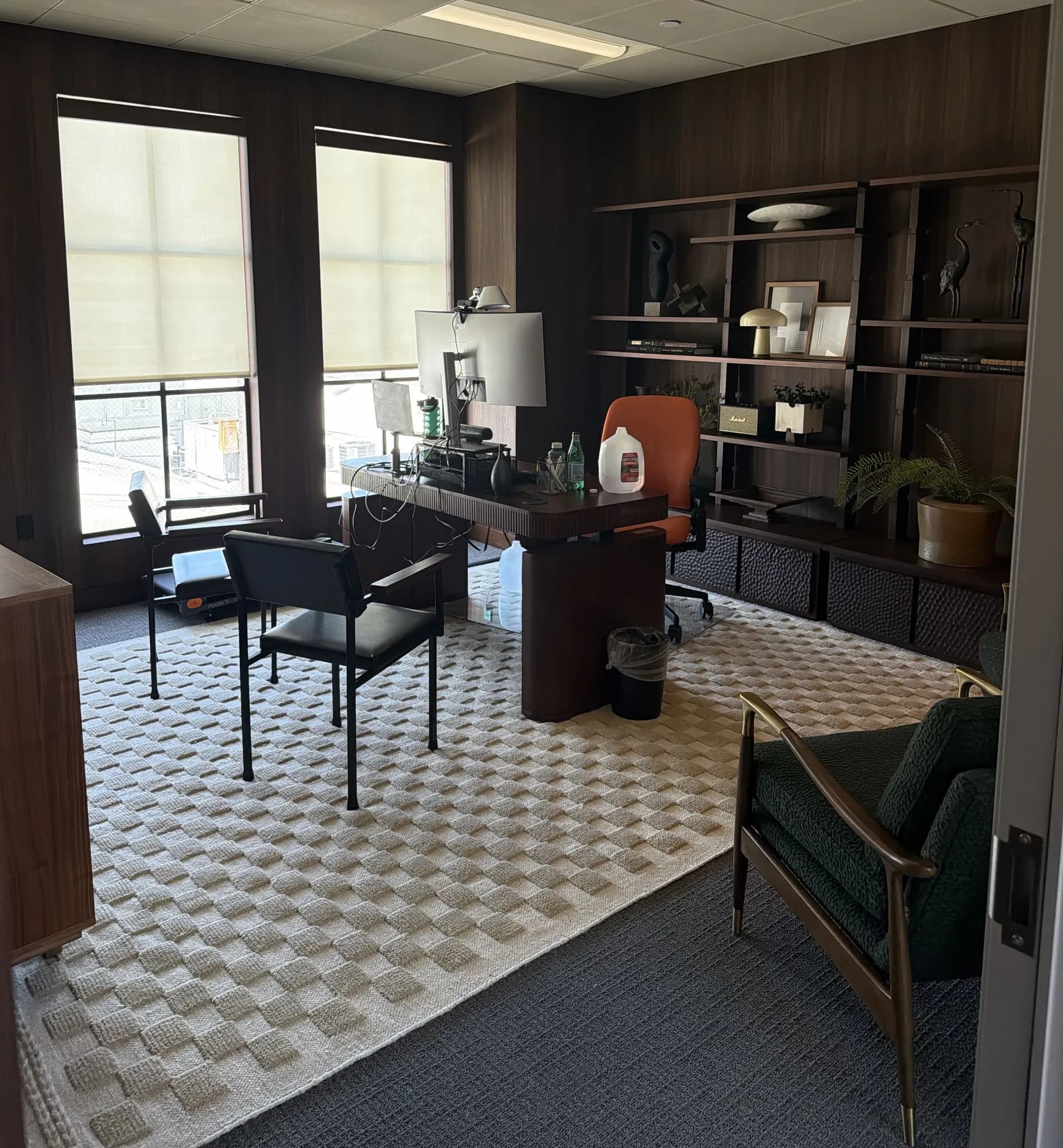 Executive office with built-in walnut shelving and a woven rug