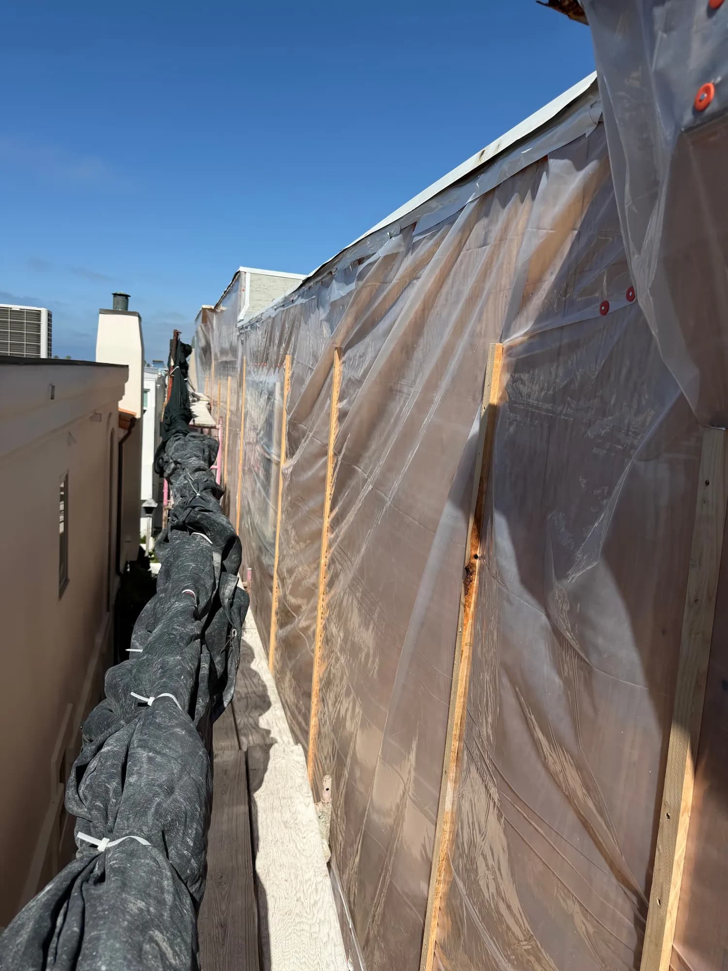 Plastic sheeting battened over open sheathing ahead of rain