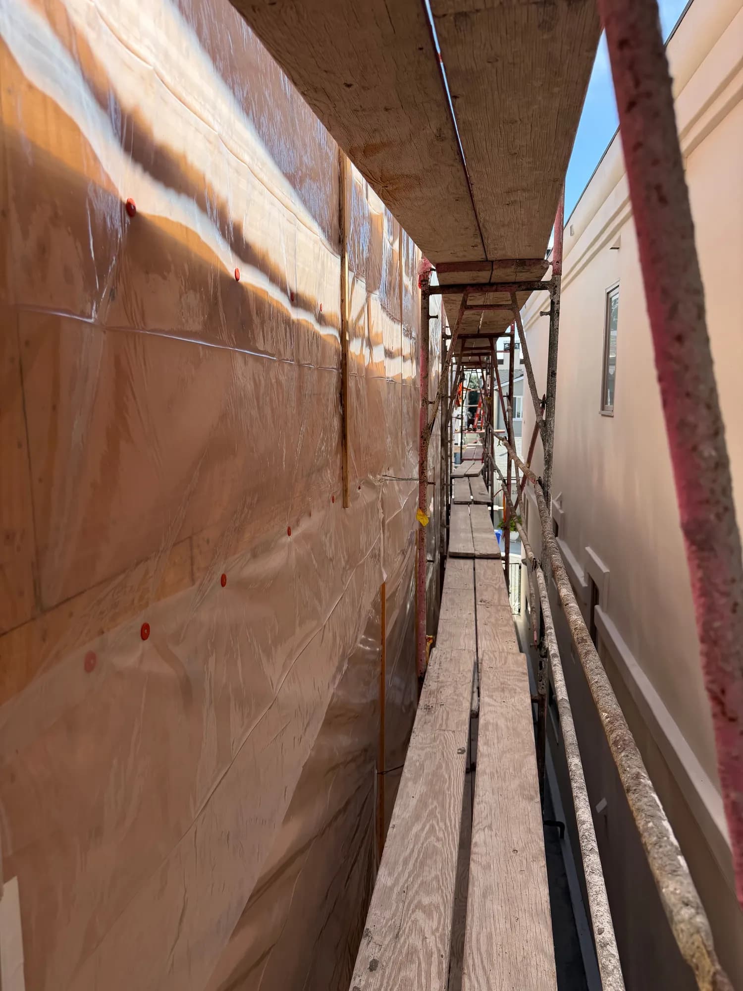 Scaffold walkway along a sheeted wall protected from rain